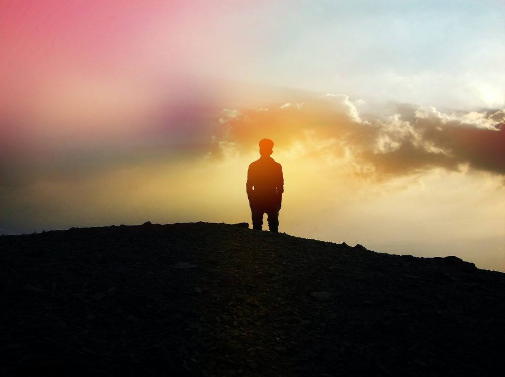 Man standing on hill at sunset
